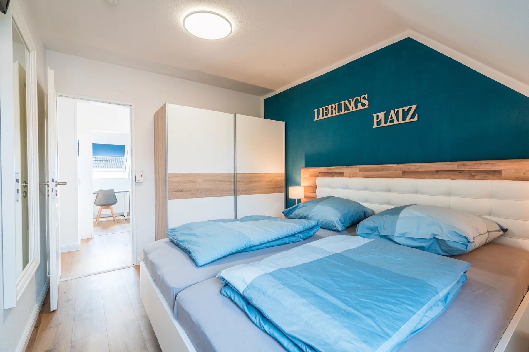 Schlafzimmer mit Doppelbett und blauer Akzentwand